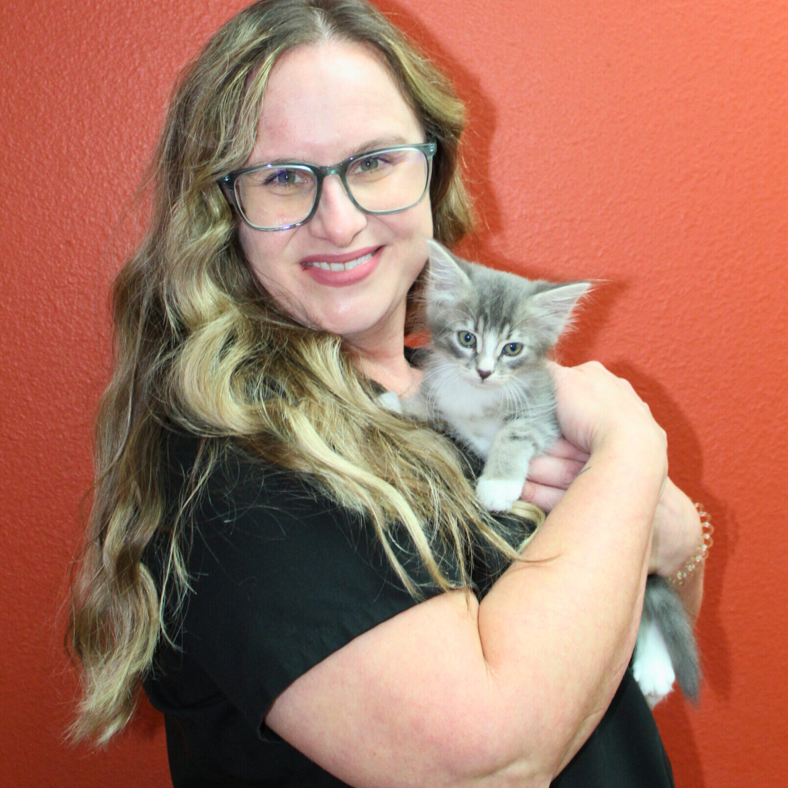 smiling female veterinarian turned towards the right and holding a kitten